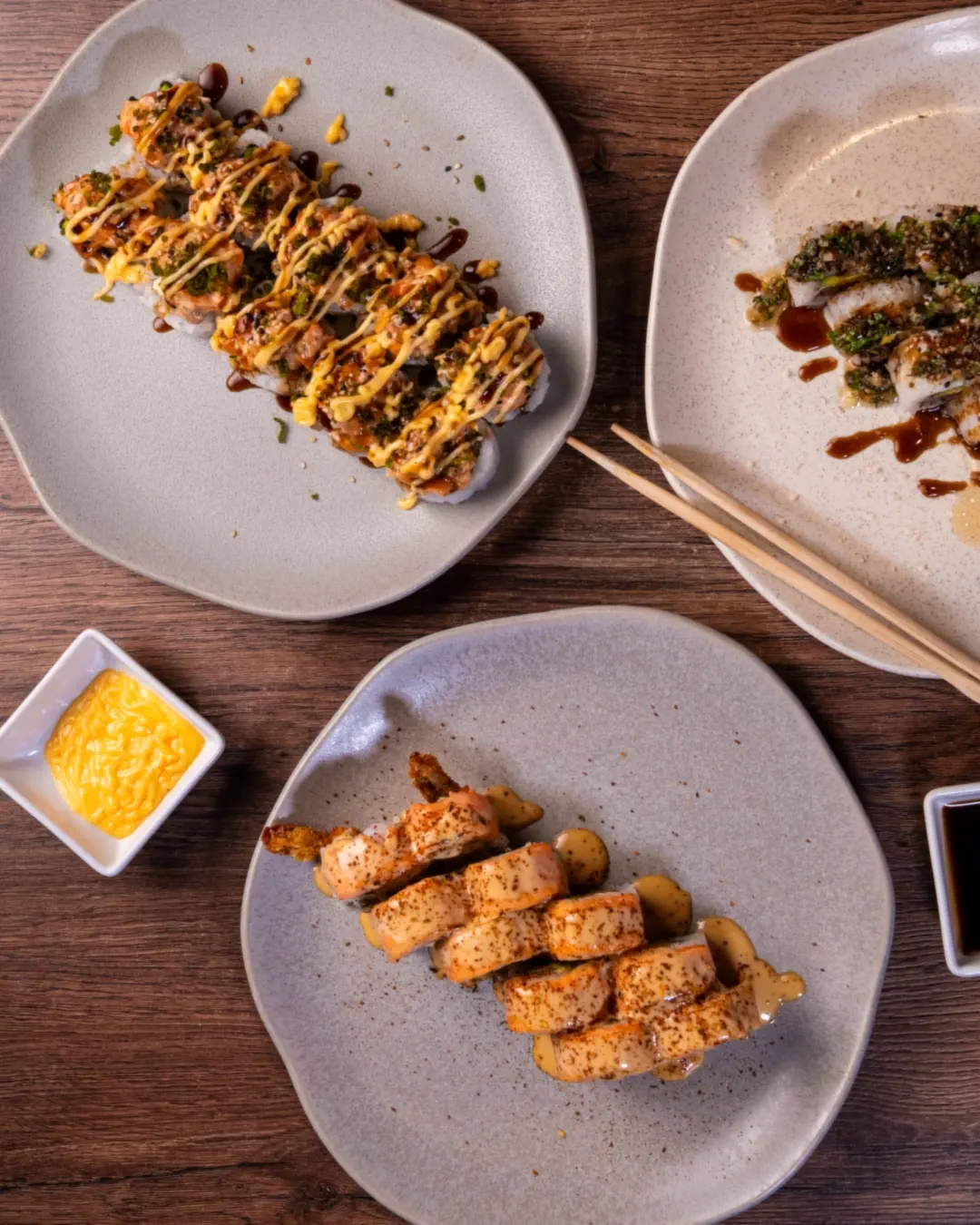 Mesa compartida con tres platos de rollos y salsas en Orientaru